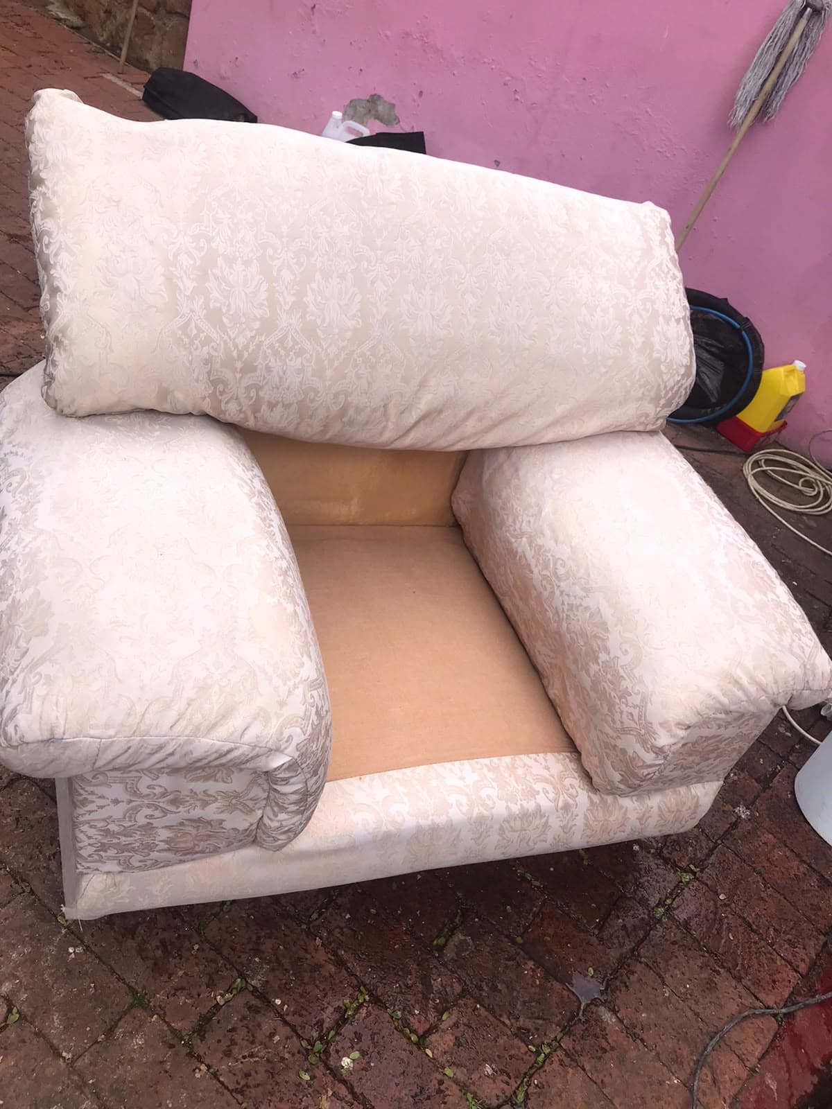 The matching armchair with visibly cleaner patterned upholstery and its seat cushion removed.